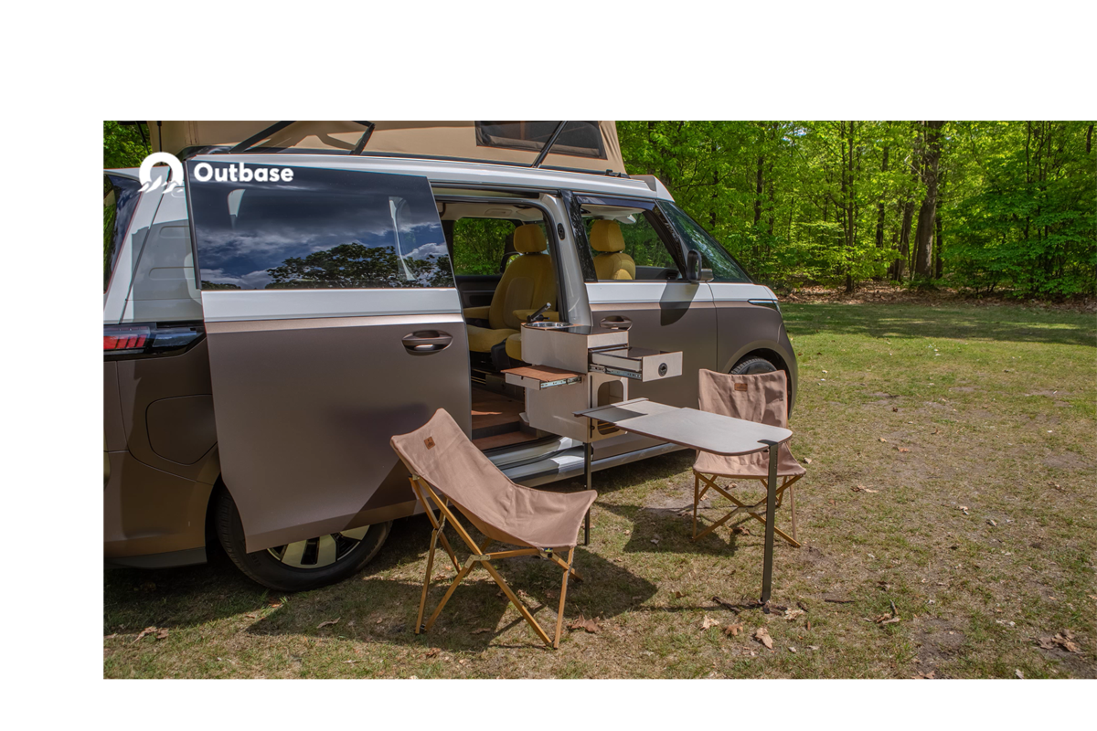 Met de draaibare keuken van de Outbase ID.Buzz kun je zowel binnen als buiten koken. De afbeelding laat een koppel zien wie binnen de camper zitten te ontbijten en koffie zetten op de draaibare keuken. 