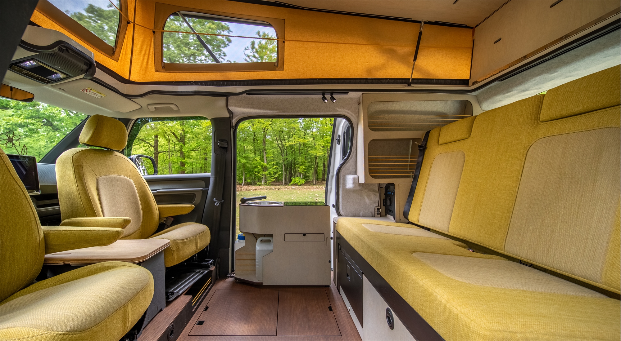Interieur van een compacte camperbus met draaibare stoelen en slimme ingebouwde keukenoplossing