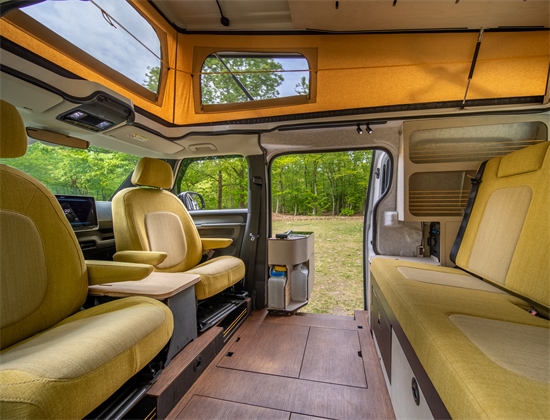 Detail van het Outbase-logo op houten keukenmodule in elektrische camperbus, met focus op duurzaam design en afwerking.